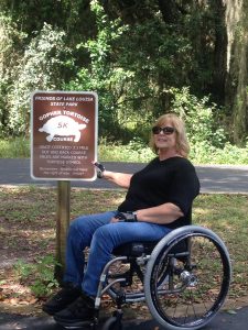 Photo of Joyce Tucker in wheelchair at park entrance