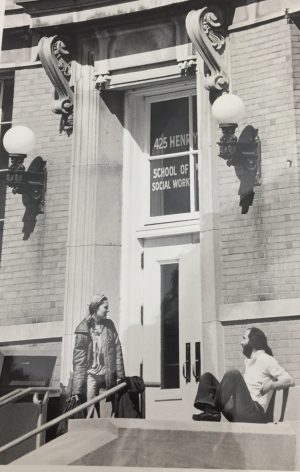 Black and white photo; students sitting on steps outside