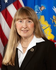 Dr. Silvia Jackson, a light-skinned woman with long blond hair in black blazer with white collar shirt. 