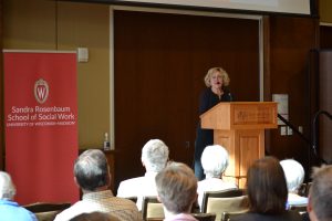 Roberta Gassman standing at podium speaking into microphone