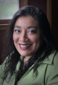 Nancy Saíz sitting inside, wearing green jacket