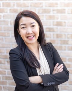 Sheng Lee Yang smiling in a black blazer with crossed arms
