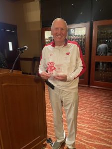 Bob Mohelnitzky standing with this alumni award next to a podium
